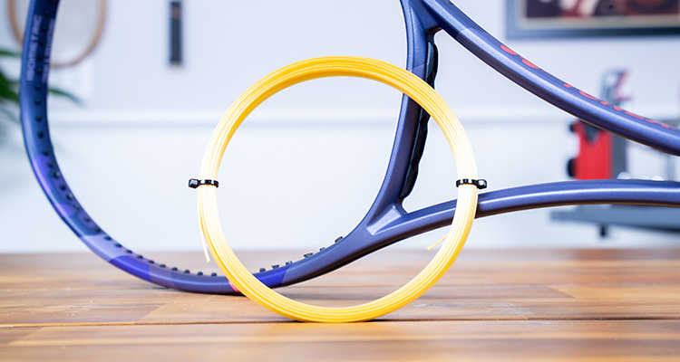 A Set of Luxilon 4G Leaning Against a Tennis Racquet